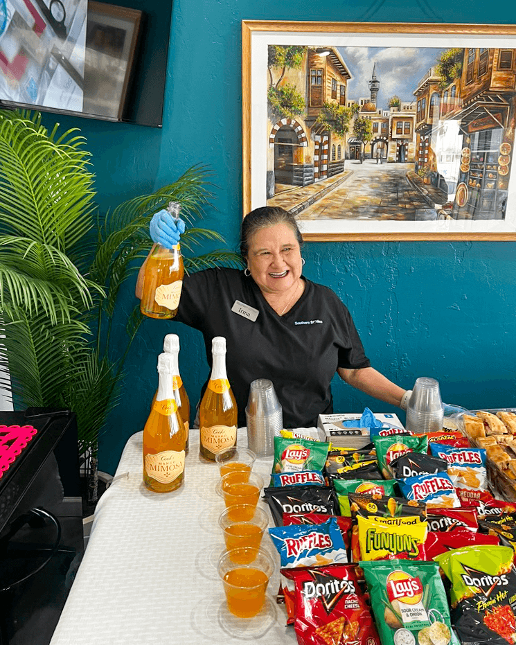 A smiling Southern Smiles team member stands behind the refreshment table with drinks and snacks.
