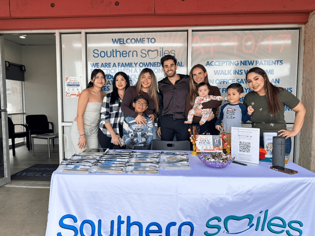 Adults and children gather behind the Southern Smiles welcome table outside the office during the open house.