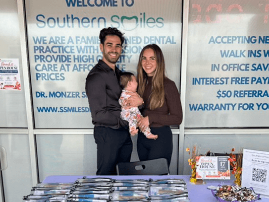 Two adults pose with a baby outside Southern Smiles during the open house.